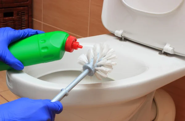 Mão de mulher em luva azul limpeza vaso sanitário — Fotografia de Stock