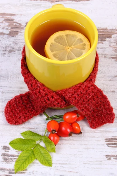 Cup of hot tea with lemon wrapped woolen scarf, warming beverage for flu, autumn decoration — Stock Photo, Image