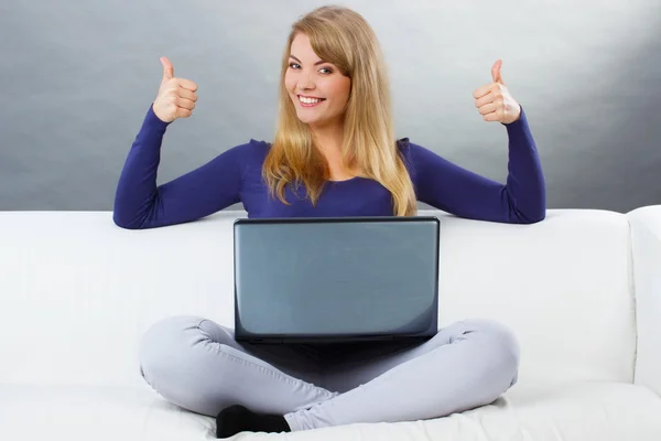 Mujer feliz usando el portátil sentado en el sofá y mostrando los pulgares hacia arriba — Foto de Stock