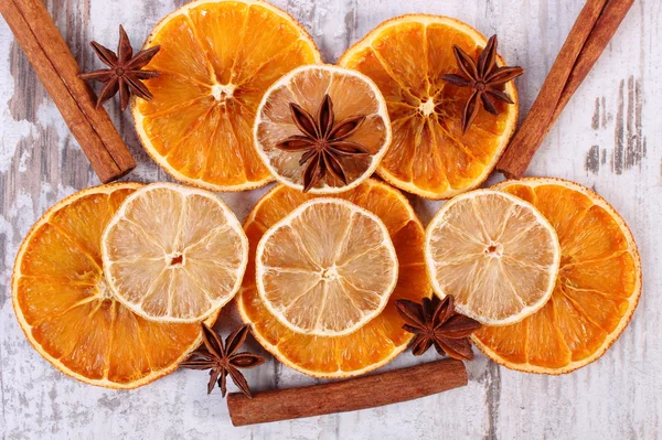 Slices of dried lemon, orange and spices on old wooden background — Stock Photo, Image