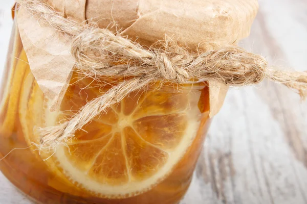 Лимон с медом в стеклянной банке на деревянном столе, здоровое питание — стоковое фото