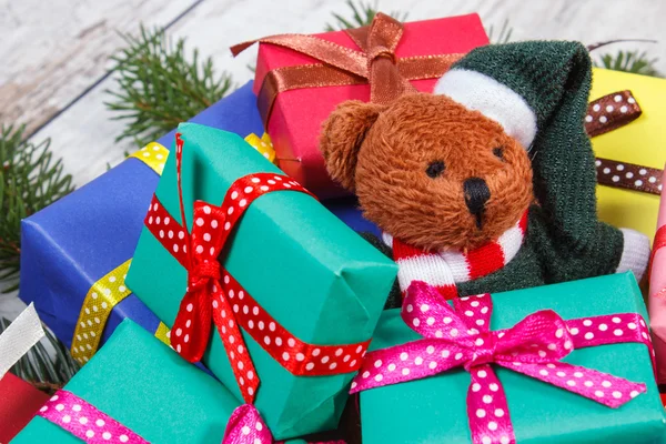 Osito de peluche con coloridos regalos para Navidad y ramas de abeto — Foto de Stock