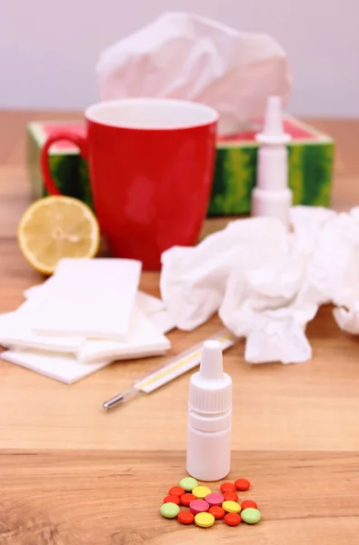 Tabletták és az orr csepp a megfázás, használt zsebkendők és forró teát citrommal — Stock Fotó