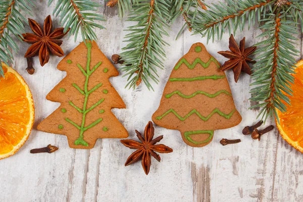 Decorated gingerbread, spruce branches, spices on old wooden background, christmas decoration — Stock Photo, Image