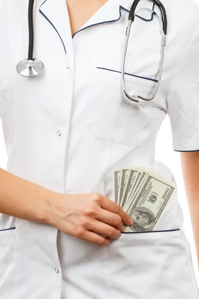 Mujer doctora con estetoscopio y monedas dólar en bolsillo delantal, concepto de corrupción o soborno — Foto de Stock