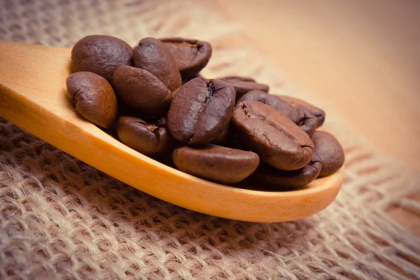 Vintage photo, Heap of coffee beans with wooden spoon on jute canvas — Stock Photo, Image