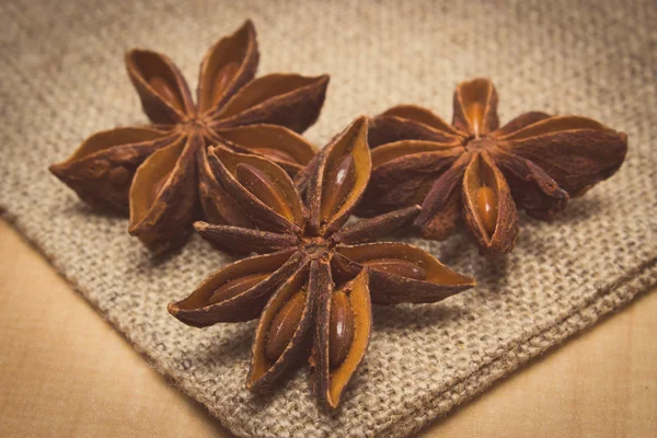 Vintage photo, Star anise on jute canvas on wooden table, seasoning for cooking — Stok fotoğraf