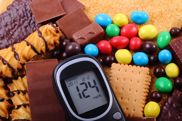 Glucometer com montão de doces e açúcar mascavo de cana, comida não saudável — Fotografia de Stock