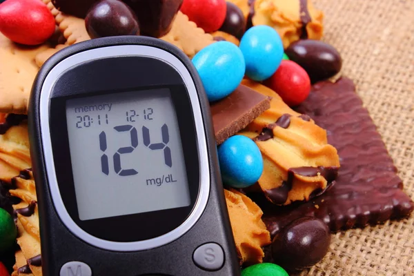 Glucometer with heap of sweets on jute burlap, diabetes and unhealthy food — Stock Photo, Image