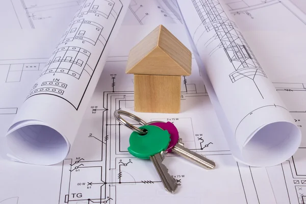 House of wooden blocks, rolls of diagrams and keys on construction drawing of house — Stock Photo, Image