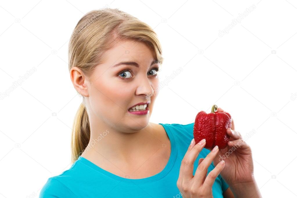 Disgusted woman holding in hand old wrinkled peppers, white background