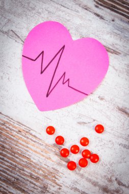 Heart of paper with cardiogram line and supplement pills, medicine and healthcare concept