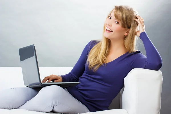 Mujer feliz usando el ordenador portátil sentado en el sofá, la tecnología moderna —  Fotos de Stock