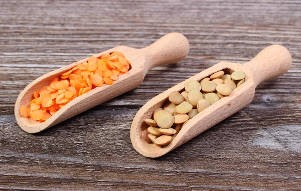 Green and red lentil with spoon on wooden background — Stock Photo, Image