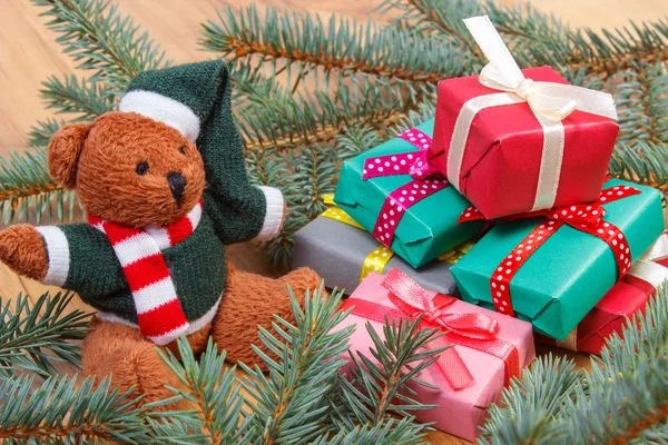Medvídek s barevnými dárky na Vánoce a smrkové větve — Stock fotografie