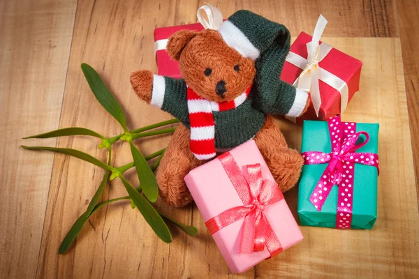 Teddy bear with colorful gifts for Christmas and mistletoe — Stock fotografie
