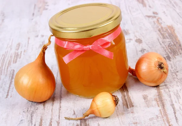 Miel orgánica fresca en frasco de vidrio y cebollas sobre fondo de madera, nutrición saludable y fortalecimiento de la inmunidad — Foto de Stock