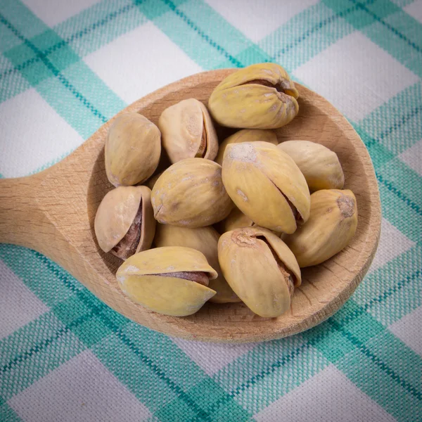 Nueces de pistacho con cuchara en mantel a cuadros, alimentación saludable —  Fotos de Stock