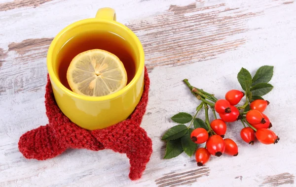 Cup of tea with lemon wrapped woolen scarf, warming beverage for flu, autumn decoration — Stock Photo, Image