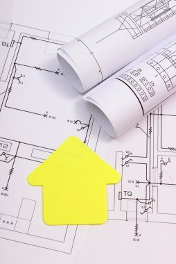 House of yellow paper and rolls of diagrams on construction drawing