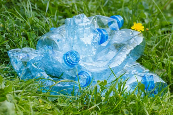 Plastic bottles of mineral water on grass in park, littering of environment — Stock Photo, Image