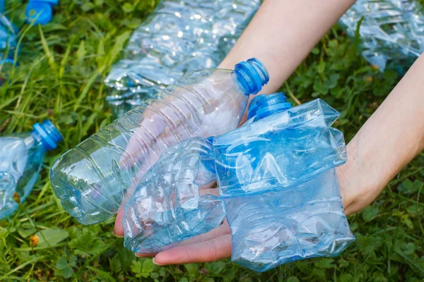 Garrafas de plástico de água mineral na mão da mulher, lixo de ambiente — Fotografia de Stock