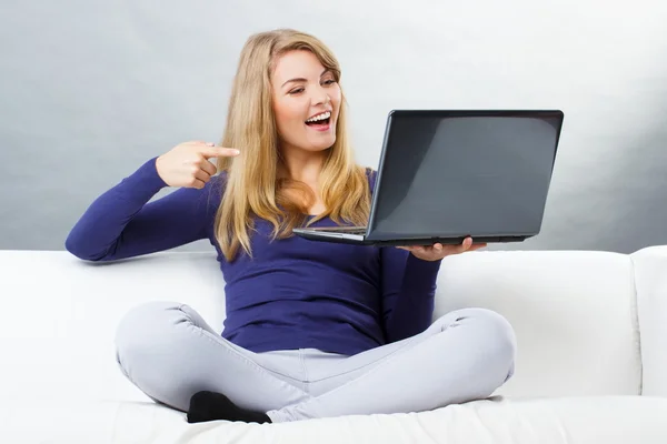 Mujer feliz sentado en el sofá y mostrando el ordenador portátil, la tecnología moderna — Foto de Stock