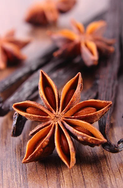 Closeup de anis estrelado e baunilha perfumada na prancha de superfície de madeira — Fotografia de Stock