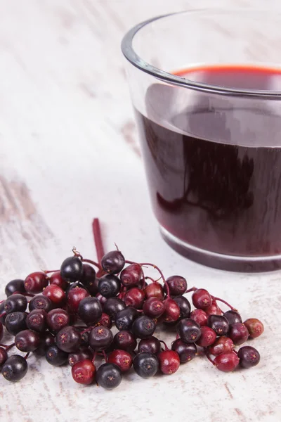 Bunch of fresh elderberry with juice on old wooden background, healthy nutrition — Stock Photo, Image