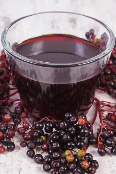 Bunch of fresh elderberry with juice on old wooden background, healthy nutrition — Stock Photo, Image