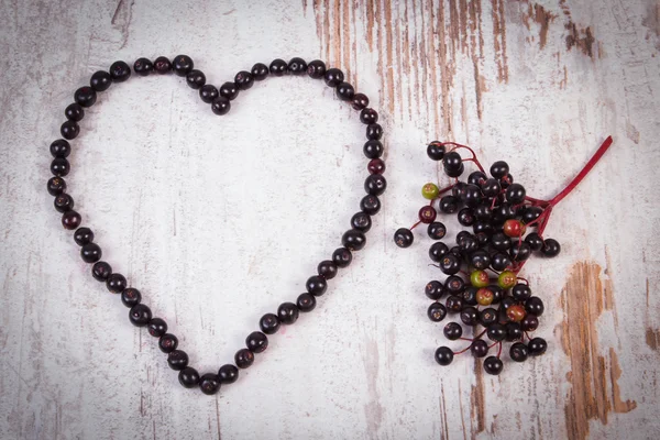 古い木製の背景、愛のシンボルに新鮮なニワトコの心 — ストック写真
