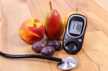 Glucose meter with medical stethoscope and fresh fruits, healthy lifestyle