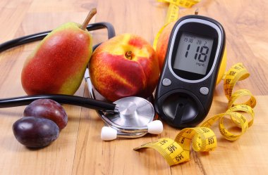 Glucose meter with medical stethoscope and fresh fruits, healthy lifestyle