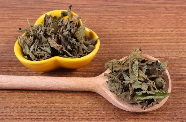 Dried lemon balm with spoon and bowl on wooden table, herbalism — ストック写真