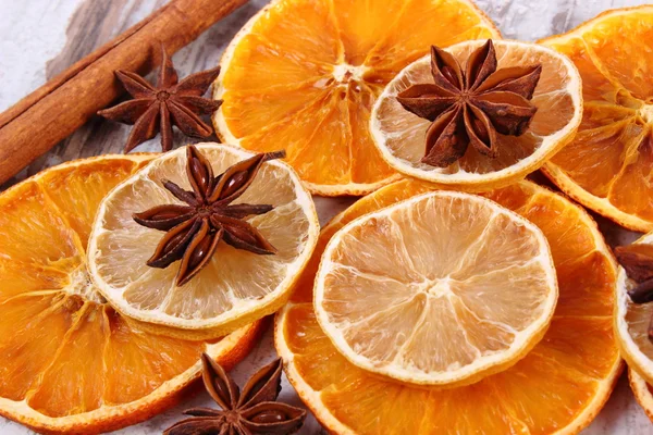 Slices of dried lemon, orange and spices on old wooden background — Stock Photo, Image