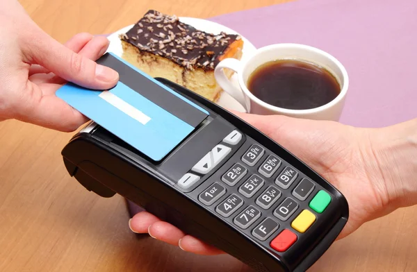 Paying with contactless credit card for cheesecake and coffee in cafe, finance concept — Stock Photo, Image