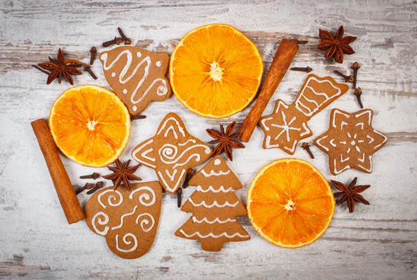 Fresh baked decorated gingerbread with spices on old wooden background, christmas time — Stock Photo, Image