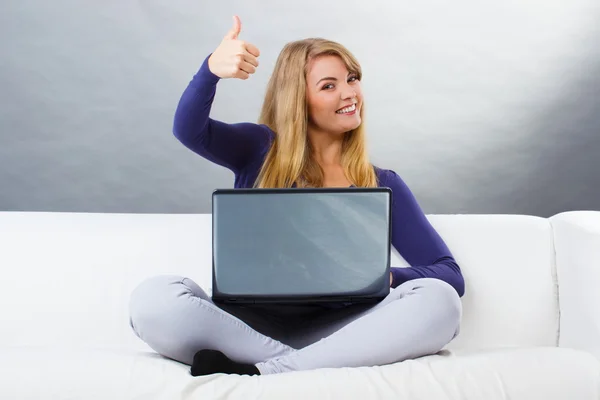 Mujer feliz usando el portátil sentado en el sofá y mostrando los pulgares hacia arriba — Foto de Stock