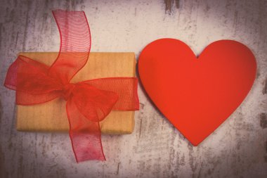 Vintage photo, Wrapped gift for Valentines day and red heart on old wooden table