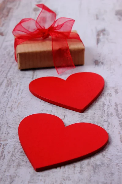 Corazones rojos y regalo envuelto para el día de San Valentín en la vieja mesa de madera — Foto de Stock