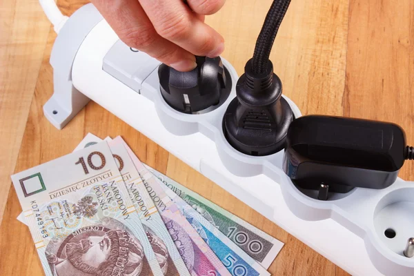 Hand of woman turns off electrical plug, polish currency money, energy costs — Stock Photo, Image