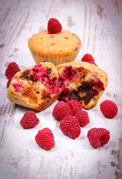 Fresh baked muffins with chocolate and raspberries on wooden background, delicious dessert — Stock Photo, Image