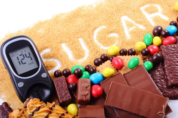 Glukometer, brauner Rohrzucker und jede Menge Süßigkeiten — Stockfoto