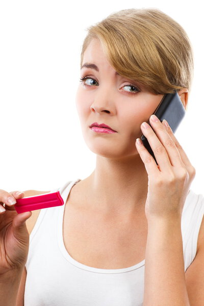 Worried woman with phone informing someone about positive pregnancy test