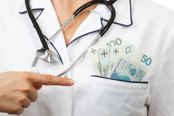 Woman doctor with stethoscope showing polish currency money in apron pocket, corruption or bribe concept — Stockfoto