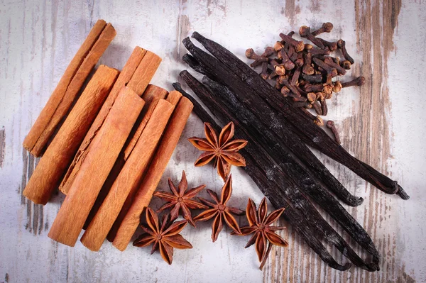 Varas de canela, baunilha, anis estrelado e cravo na superfície de madeira — Fotografia de Stock