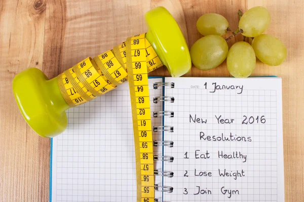 New years resolutions written in notebook and dumbbells with centimeter — Stok fotoğraf
