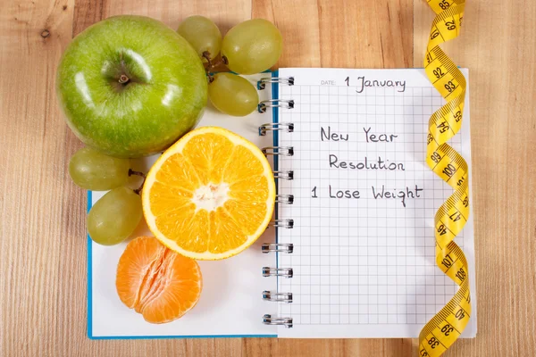New years resolutions written in notebook and tape measure — Stock Photo, Image