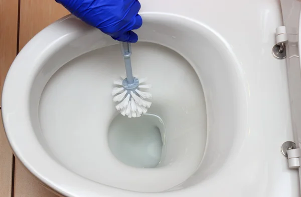 Hand einer Frau in blauem Handschuh reinigt Toilettenschüssel — Stockfoto