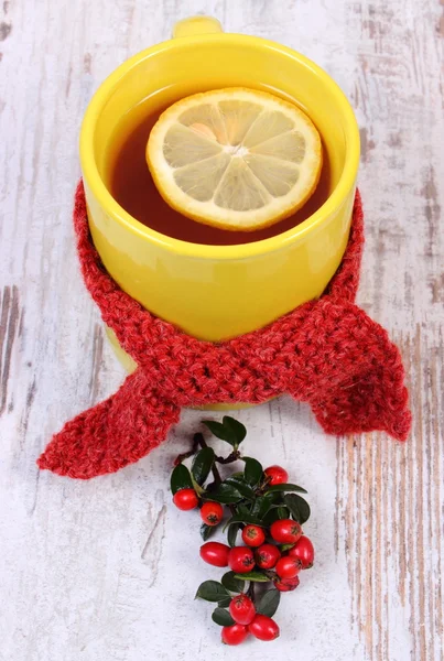 Xícara de chá quente com cachecol de lã envolto de limão e cotoneaster, bebida de aquecimento para a gripe — Fotografia de Stock